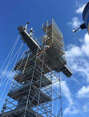 scaffold set up around a tall structure against a blue sky