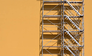 scaffolding with stairs next to an orange wall