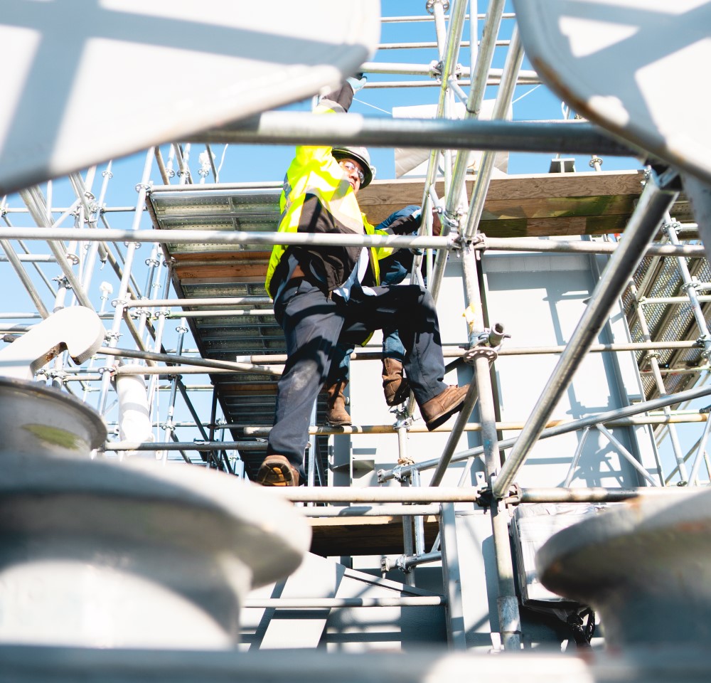 two workers climbing on scaffolding at a job site